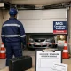 Técnico inspecciona una puerta de garaje dañada, con conos, coche detenido y documentos; Encuentra expertos en reparacion de puertas de garaje en Valencia para contratacion inmediata